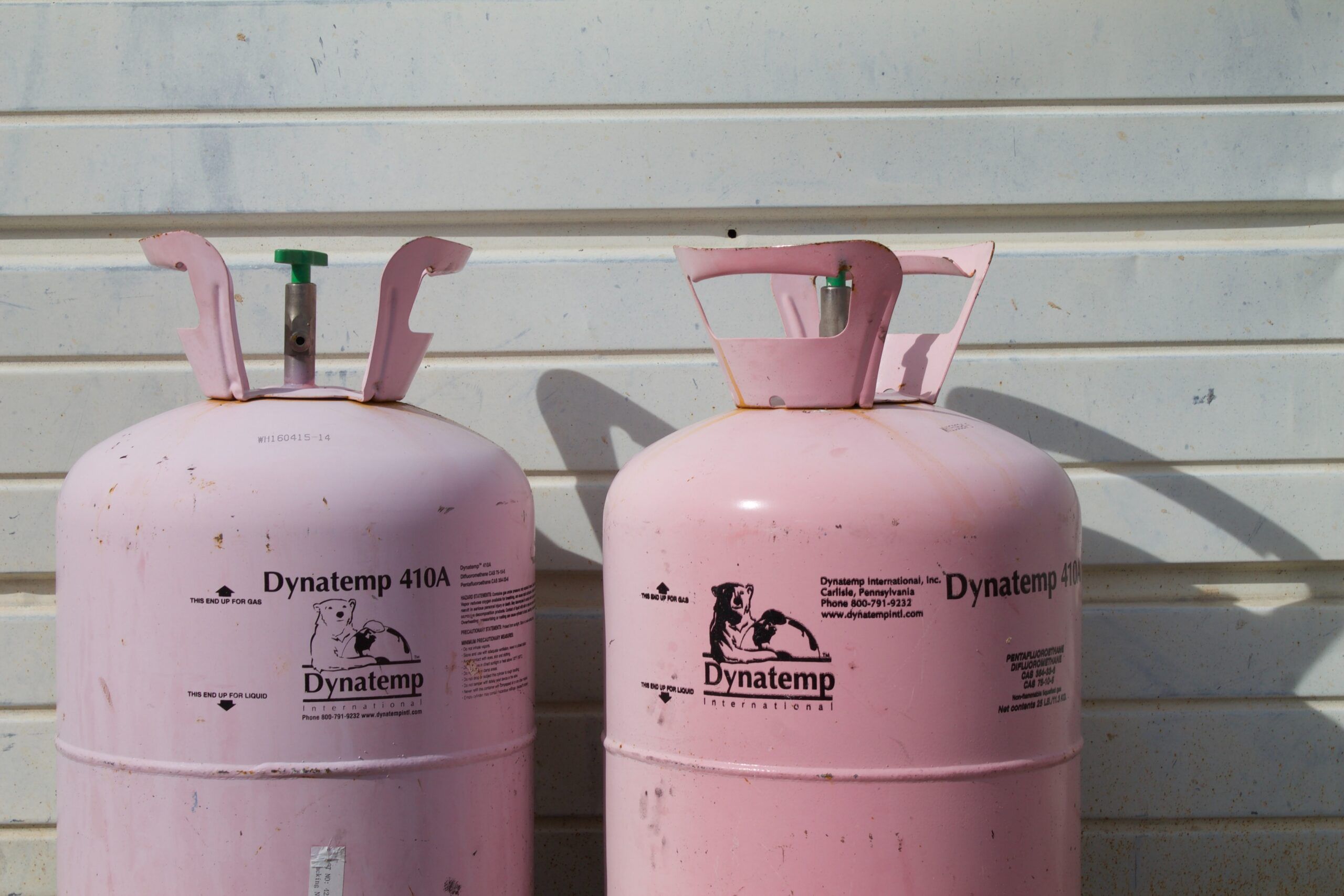 Pink gas bottles in front of a white wooden wall